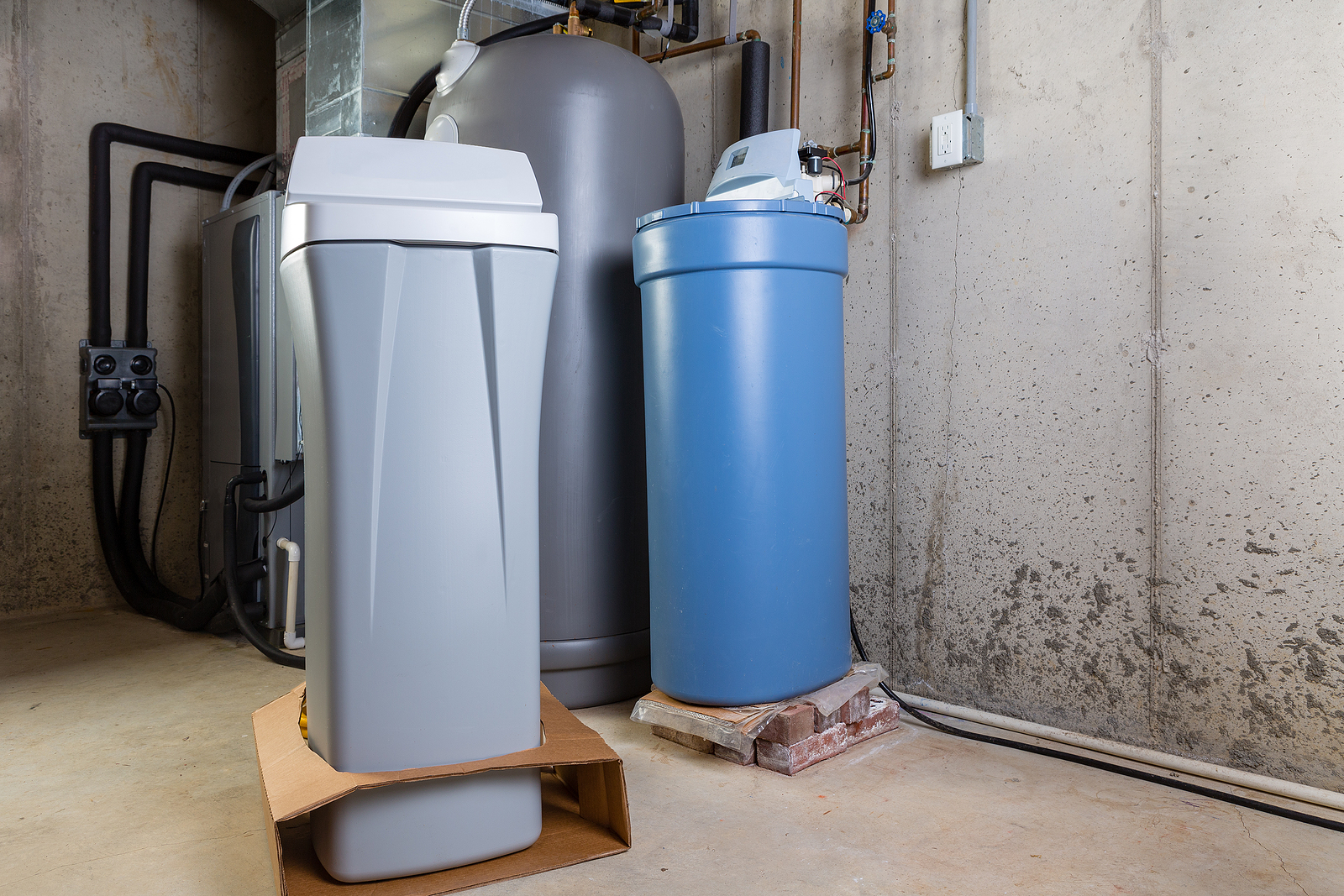 Compact water softener and brine tank setup in a basement, removing hard minerals for appliance protection