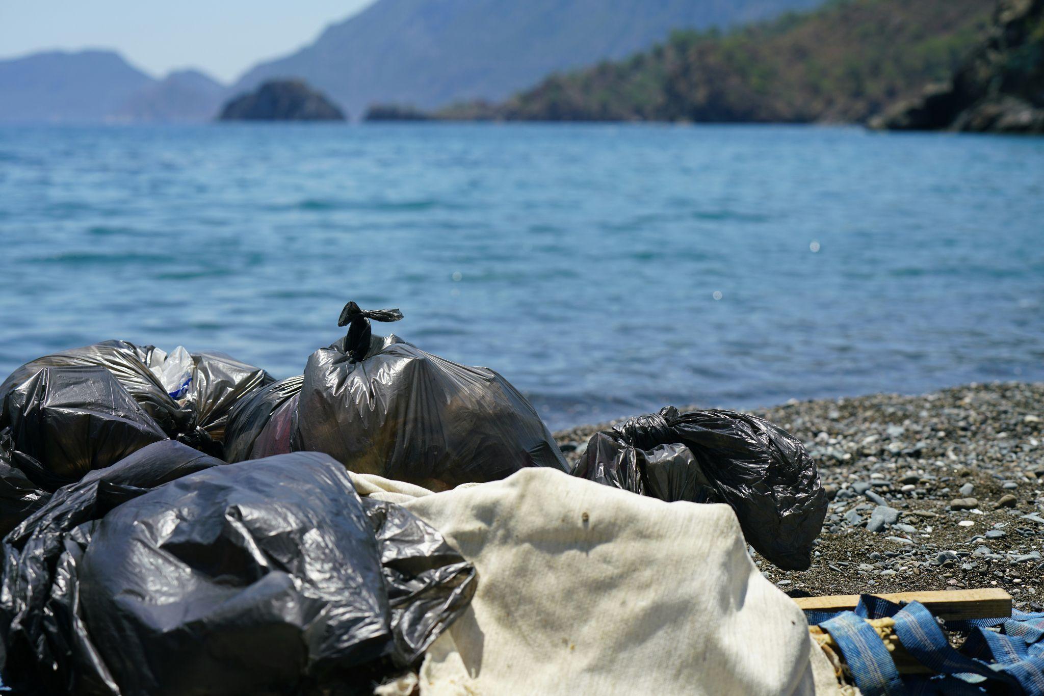 Volunteers cleaning trash from a riverbank, representing community efforts to reduce water pollution and protect the environment.