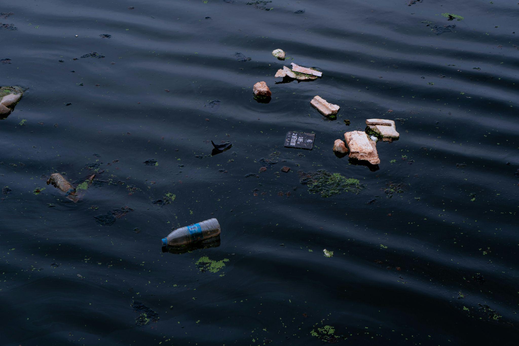 Garbage floating on a contaminated waterway, highlighting the effects of water pollution on aquatic ecosystems.