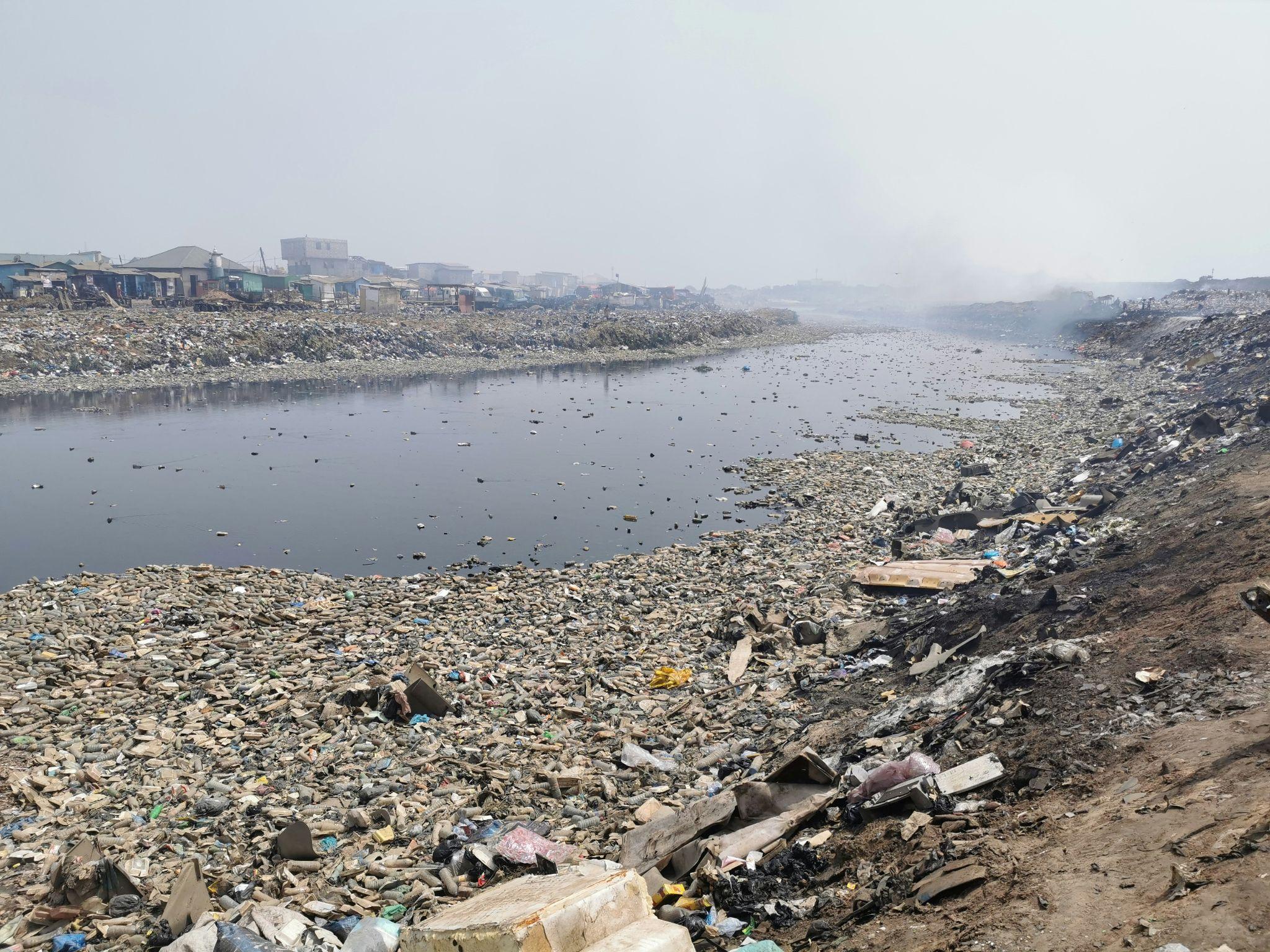 A murky polluted river with trash floating on the surface, illustrating the impact of water contamination on human and wildlife health.
