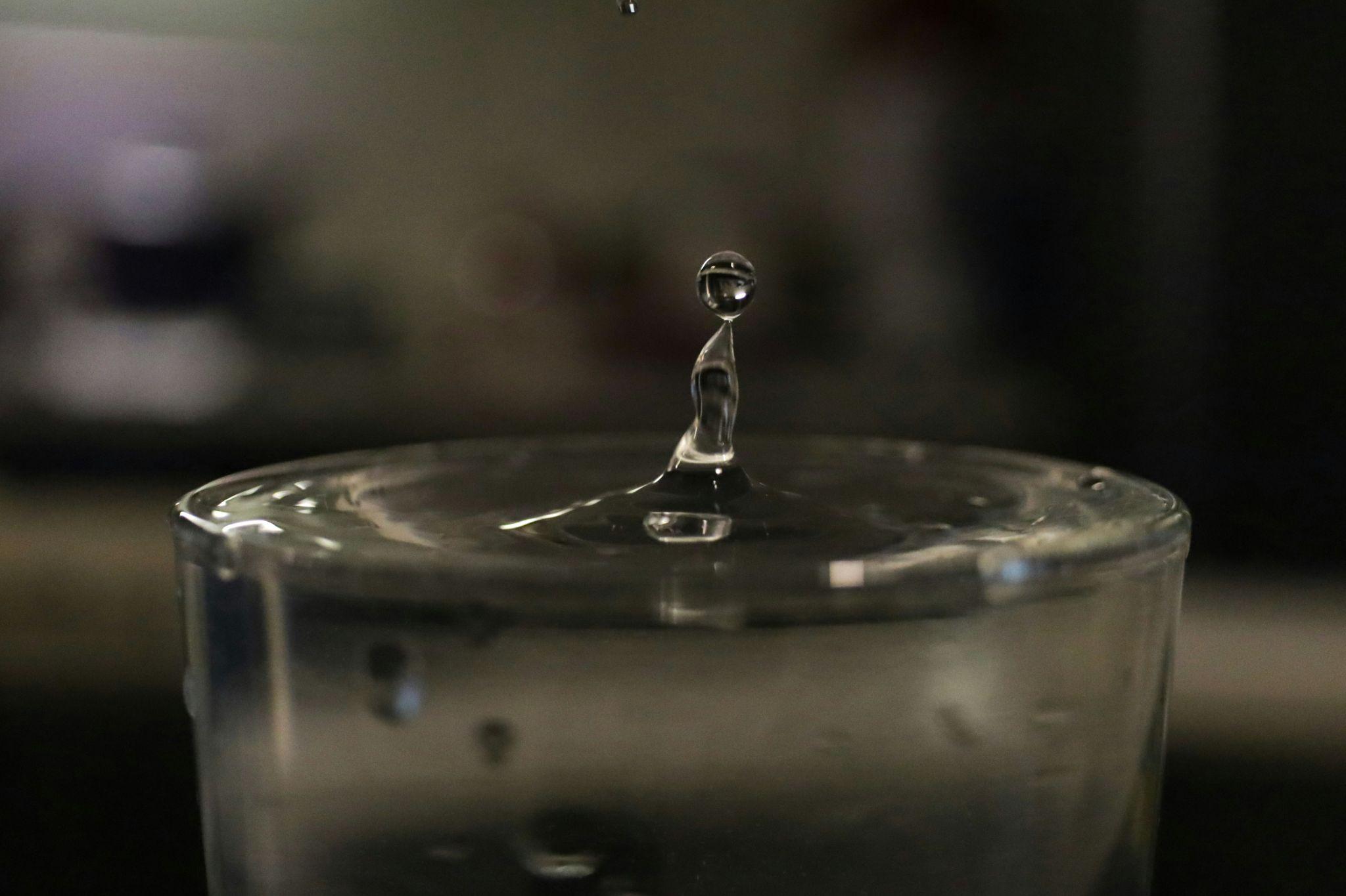 A close-up photo of a single water drop splashing into a glass, representing the purity of demineralized water.