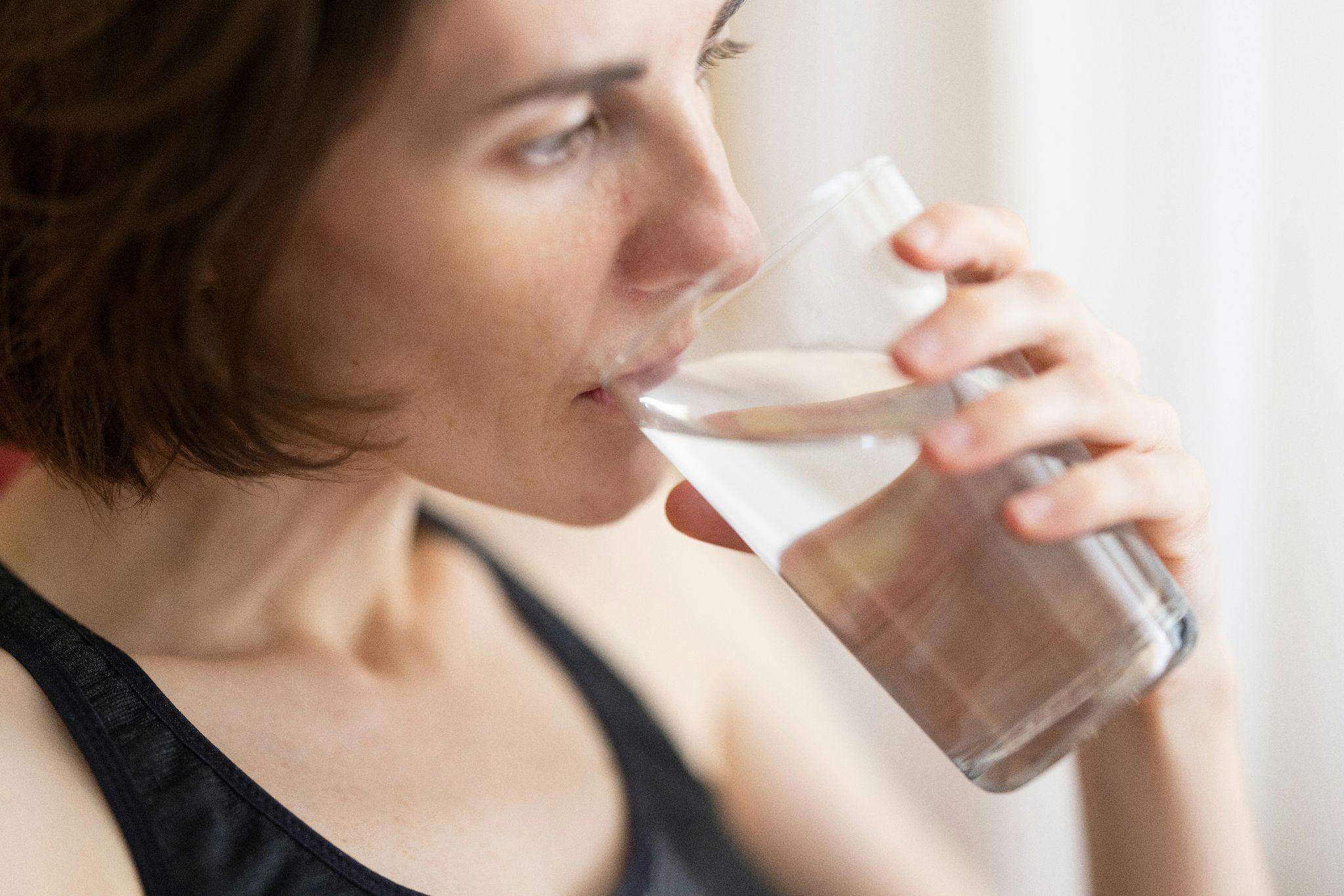A person conducting a taste test with demineralized water, comparing its flavor to regular tap water after mineral removal.