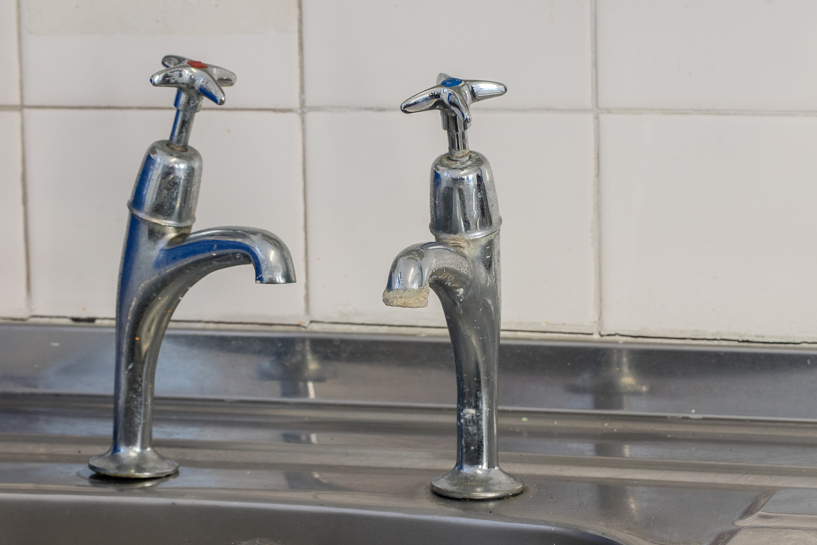 Limescale buildup on old metal tap showing effects of hard water on plumbing