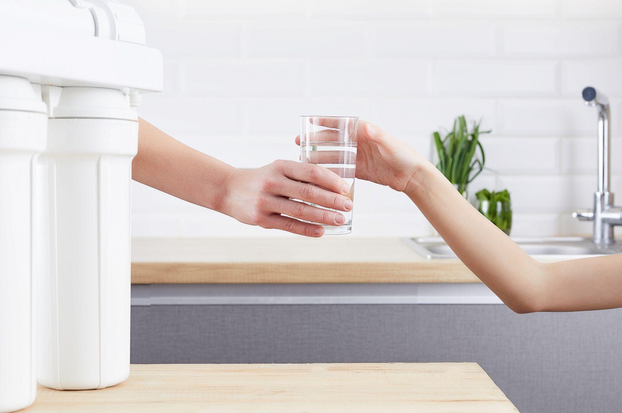 Passing a glass of conditioned water for cleaner, great-tasting tap water
