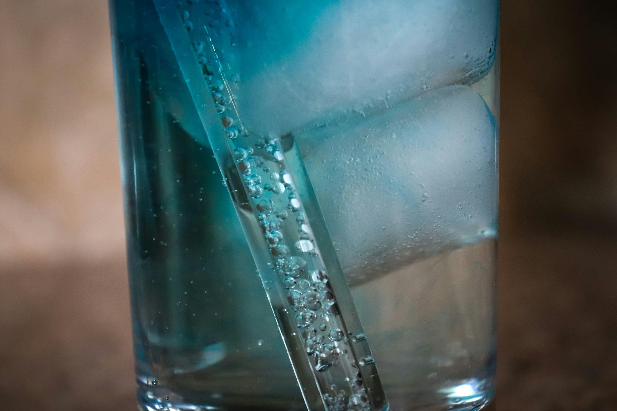 Close-up of a glass of alkaline water with ice cubes and bubbles, illustrating the refreshing look of mineralized, high-pH water.