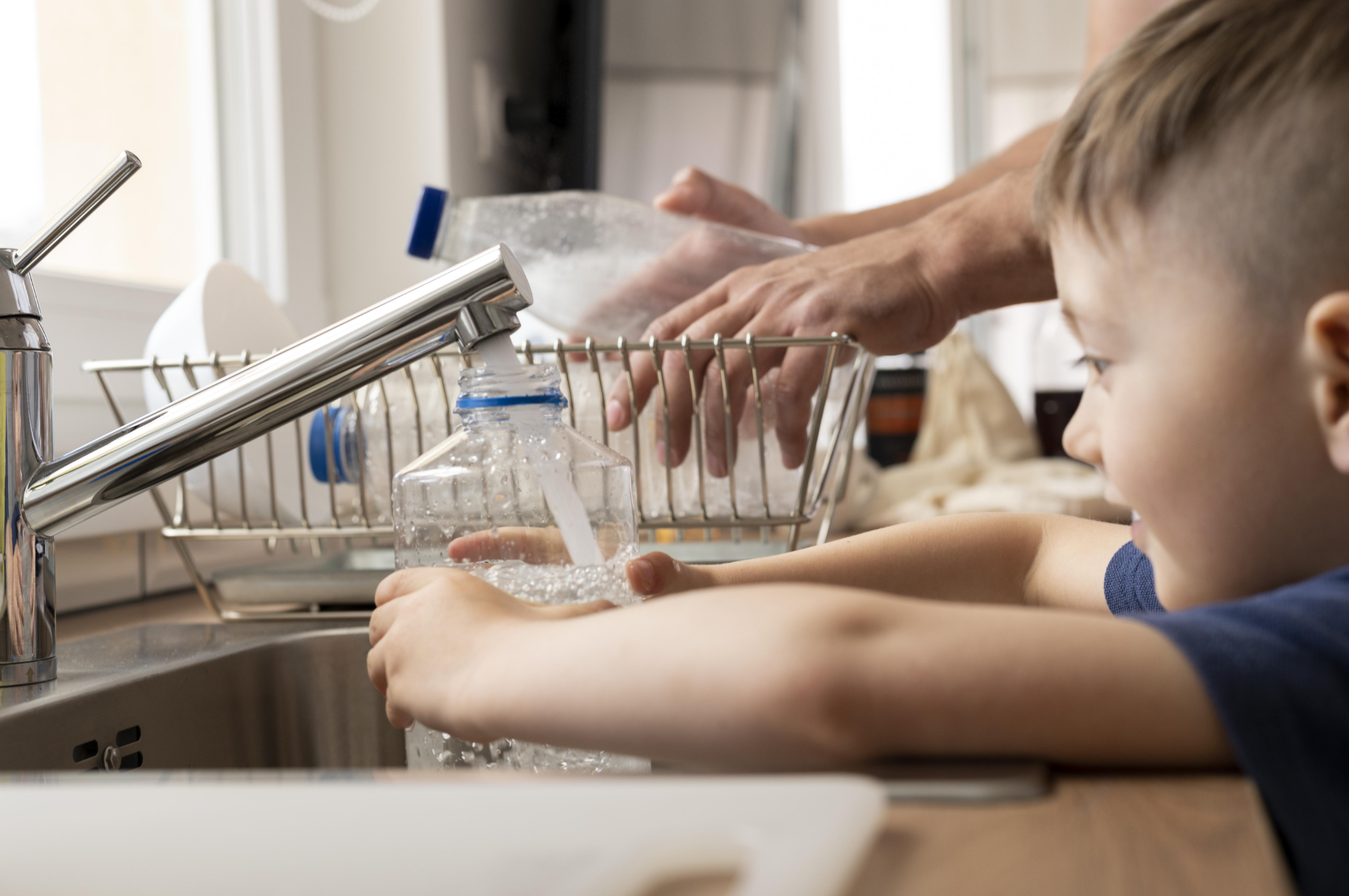 Child filling bottle at kitchen sink with RO filtered water