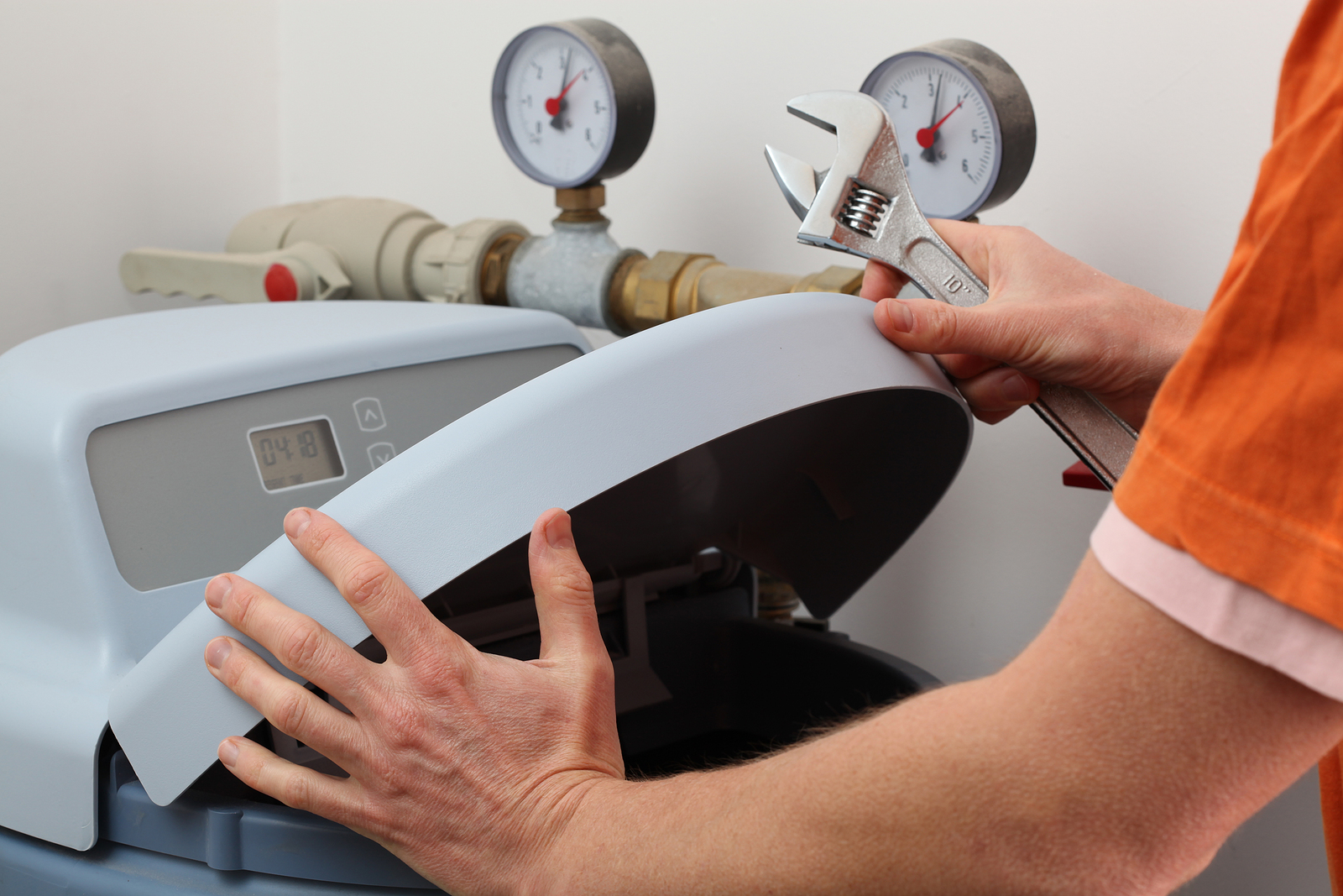 Close-up of a person performing maintenance on a water softener, demonstrating how to service systems that remove minerals from household water.
