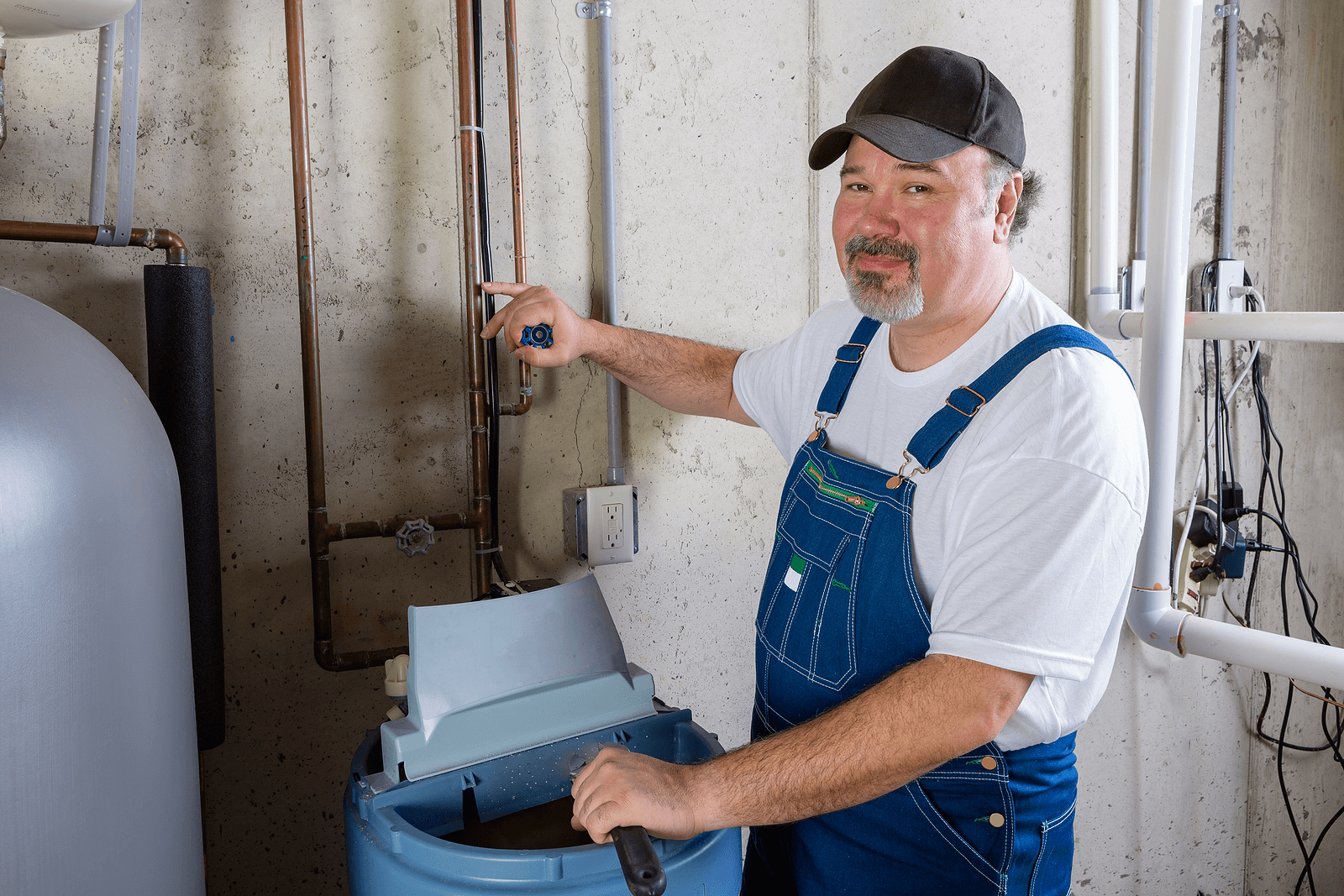 Professional technician adjusting water softener plumbing and brine tank during Phoenix installation.
